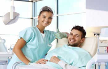 A dentist and a happy man patient after dental procedure showing his nice teeth in his smile.