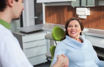 A dentist and a mature woman in a dental chair at the appointment.