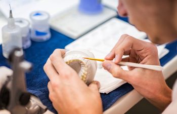 A lab technician creating a denture.