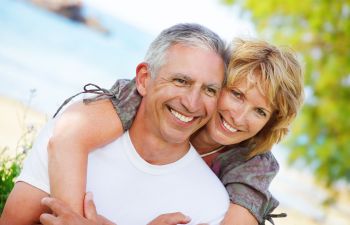 Cuddling cheerful mature couple with perfect smiles.