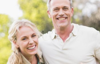 A happy middle-aged couple with perfect smiles enjoying a day outdoors.